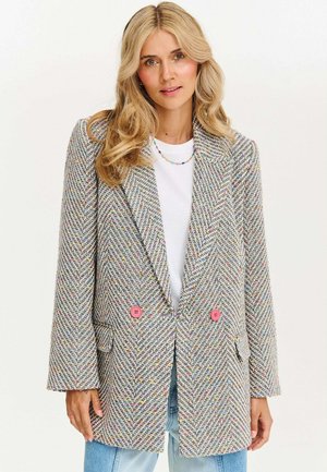 Marynarka w wzór houndstooth w wielokolorowym splotem, z dwoma różowymi guzikami, klapami i luźnym krojem. Teksturowana tkanina oraz boczne kieszenie.