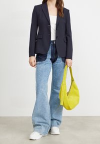 Granatowa marynarka z dwoma guzikami i kieszeniami, zestawiona z jasnoniebieskimi dzwonowatymi dżinsami. Uzupełniona jasnofioletową torebką i białymi trampkami.