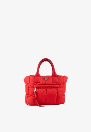 Sac à main matelassé rouge Prada avec poignées supérieures, poche zippée à l'avant et plaque triangulaire avec logo Prada sur fond blanc.