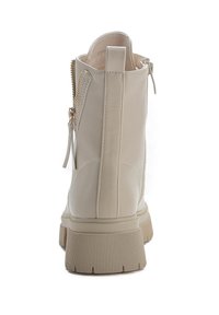 Stivaletto beige in pelle liscia con suola a carrarmato. Presenta una cerniera laterale e un'asola per una facile calzata.