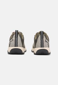 Zelené a béžové tenisky s texturovaným síťovaným svrškem, kontrastními černými akcenty a zpevněným patním okrajem. Obsahují značku Timberland.