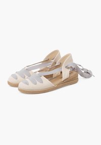 Espadrilles en toile avec une tige beige et des accents gris, présentant des sangles croisées et une semelle en corde de jute.