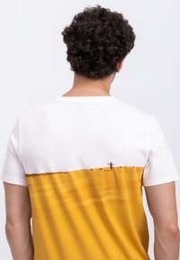 Heren t-shirt met korte mouwen, met een witte bovenkant en een mosterdgele onderkant, versierd met een subtiele landschapafbeelding en horizontale lijnen.