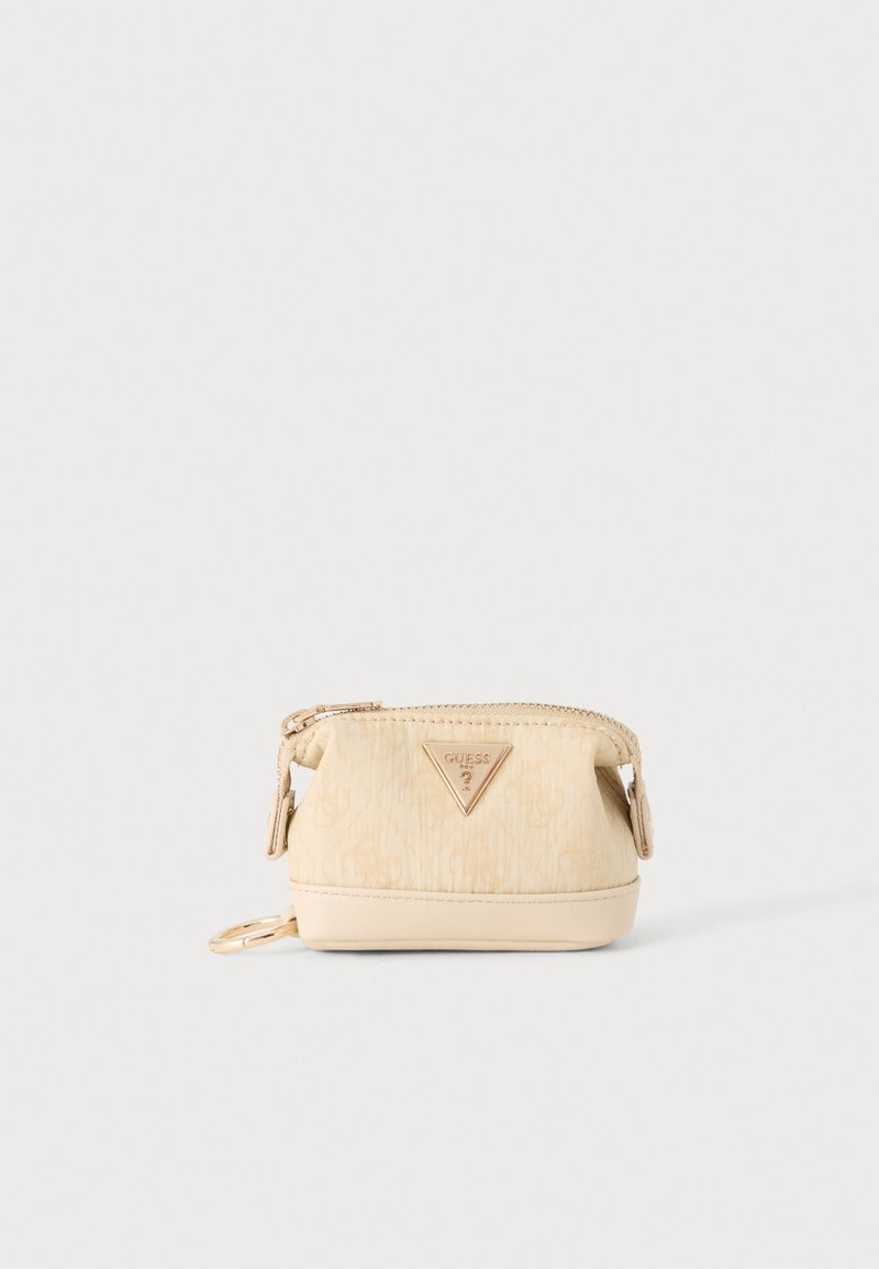 Petite pochette beige zippée avec logo triangulaire doré Guess et un porte-clés sur le côté, sur un fond uni.