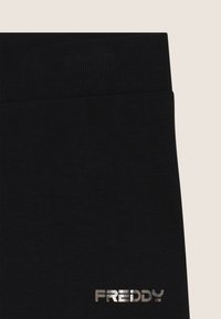 Leggings neri con vita a costine, caratterizzati da un logo "FREDDY" in argento lucido. Il tessuto sembra morbido ed elastico.