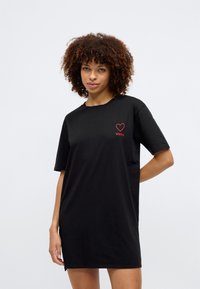 Μαύρο oversized t-shirt από βαμβάκι. Διαθέτει λογότυπο κόκκινης καρδιάς με το κείμενο "HUGO". Ευθεία γραμμή με κοντά μανίκια και στρογγυλή λαιμόκοψη.