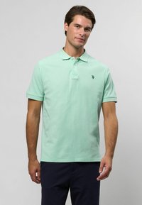 Világos menta zöld pólóing, pamutb�ól készült, klasszikus gallérral, két gombos gombolással és egy kis logóval a bal mellrészen.