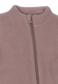 Chaqueta de forro polar en suave tono rosa, con un cuello alto y cierre central de cremallera. La textura de la tela parece acogedora y cálida.