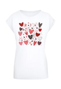 Weißes T-Shirt mit kurzen Ärmeln, das einen verspielten Druck verschiedener Herzen in Rot, Pink und Schwarz zeigt, akzentuiert mit Sternen und floralen Elementen.