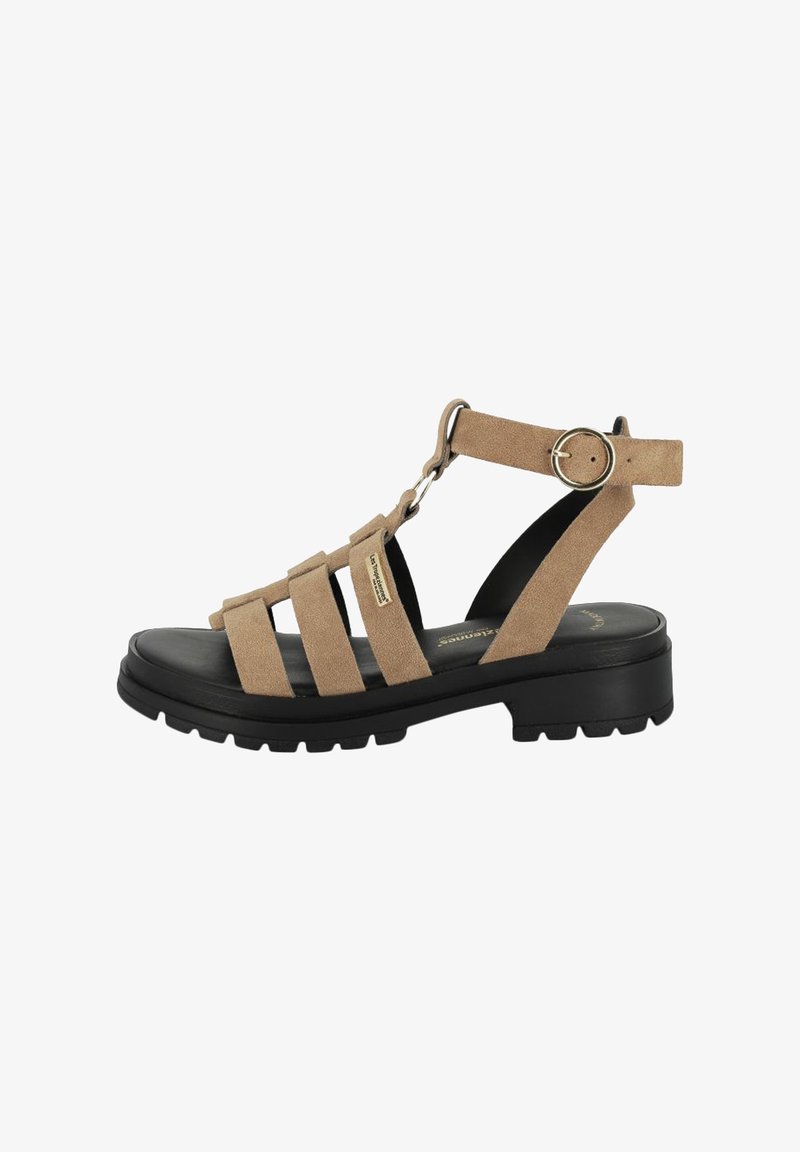 Beige suède sandalen met een T-vorm ontwerp, meerdere verstelbare banden en een robuuste zwarte zool, met een ronde gespsaccent.