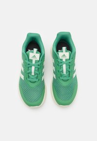 Baskets de sport vertes avec une tige en mesh texturé, des accents blancs et un design à trois bandes. Comprend un col rembourré et une semelle amortissante.