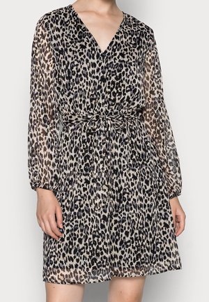 Kvinde iført en knælængde kjole med lange ærmer med sort og beige leopardprint og et knyttet bælte i taljen.