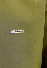 Ľanová látka olivovej zelenej farby s hladkou textúrou; obsahuje biely nápis "JACK & JONES" a farebné akcenty svetlomodrej a oranžovej.