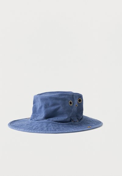 Μπλε πλατύγυρο υφασμάτινο καπέλο τύπου κουβά με μεταλλικά αεραγωγά στην κορυφή και γύρω από τη περίμετρο, σε απλό φωτεινό φόντο.