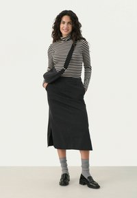 Black denim skirt with a side slit, paired with a striped turtleneck. Chunky black shoes and gray knee-high socks complete the outfit.