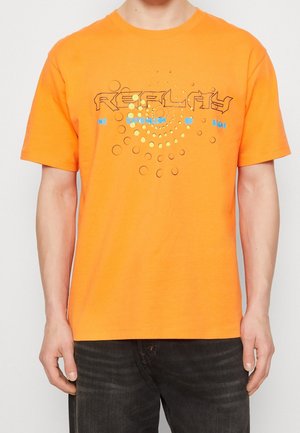 Camiseta de algodón naranja con mangas cortas. En la parte delantera presenta un gráfico circular y texto en negro y azul. Cuello redondeado y ajuste estándar.