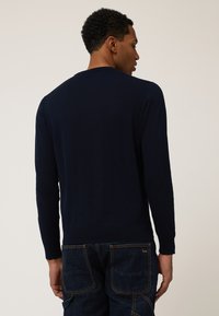 Dunkelblauer Strickpullover mit langen Ärmeln und rundem Ausschnitt, ausgestattet mit einem gerippten Saum für eine enge Passform. Glatte Textur und schlichtes Design.