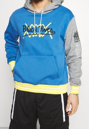Felpa blu e grigia con logo giallo, dotata di tasca frontale e orlo a righe. Il materiale sembra morbido; le maniche sono attillate e a maniche cuff.
