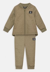 Fodrad olivgrön jacka och byxor i set med ribbade mudd och krage, med ett logomärke på bröstet och låret.