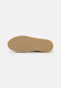 Semelle de chaussure avec une surface en caoutchouc beige lisse, arborant un motif texturé. La marque "Tamaris" et la taille "37" sont embossées sur le côté.