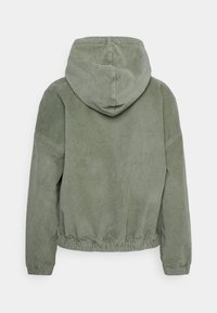 Zielona kurtka ze sztruksu z kapturem, z marszczonym dołem i teksturowaną tkaniną. Klarowny design z luźnym krojem i prążkowanymi akcentami.