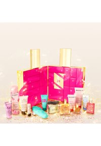Calendario dell'avvento rosa con accenti dorati aperto per rivelare una selezione di prodotti per la cura della pelle Nuxe, tra cui creme, oli e un pennello per la pulizia.