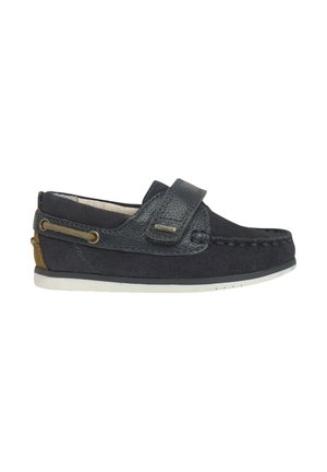 Zapatos de slip-on azul marino con parte superior de cuero texturizado, correa ajustable, detalles de costura y suela de goma blanca. Acento marrón en el talón.