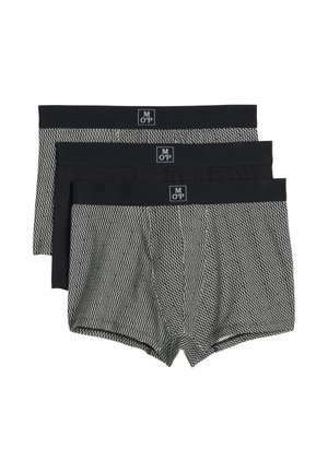 Drie paar herenslipjes met zwarte taillebanden, waarvan twee met een zwart-wit zigzagpatroon en één effen zwart in het midden.