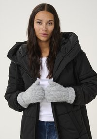 Grå strikkede handsker med et tekstureret mønster, båret af en person i en sort polstret jakke med hætte og lynlås.