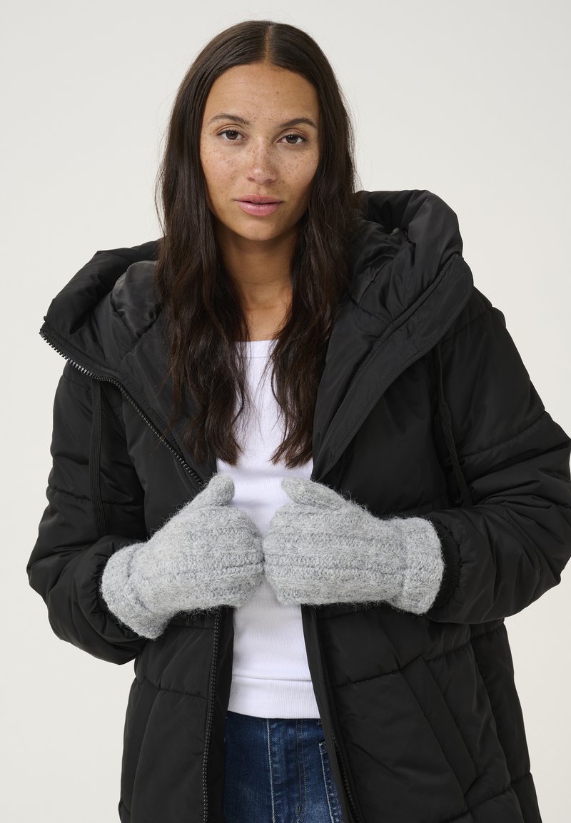 Grå strikkede handsker med et tekstureret mønster, båret af en person i en sort polstret jakke med hætte og lynlås.