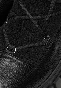 Bota de invierno negra con parte superior texturizada de material similar a la lana, detalles en cuero, puntera reforzada y suela robusta de goma con tacos.