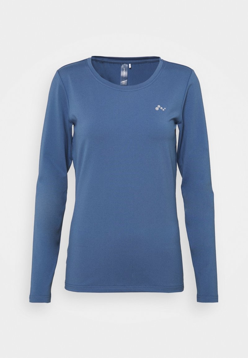 Camiseta azul de manga larga con cuello redondo, pequeño logo reflectante en el pecho izquierdo y silueta ajustada.