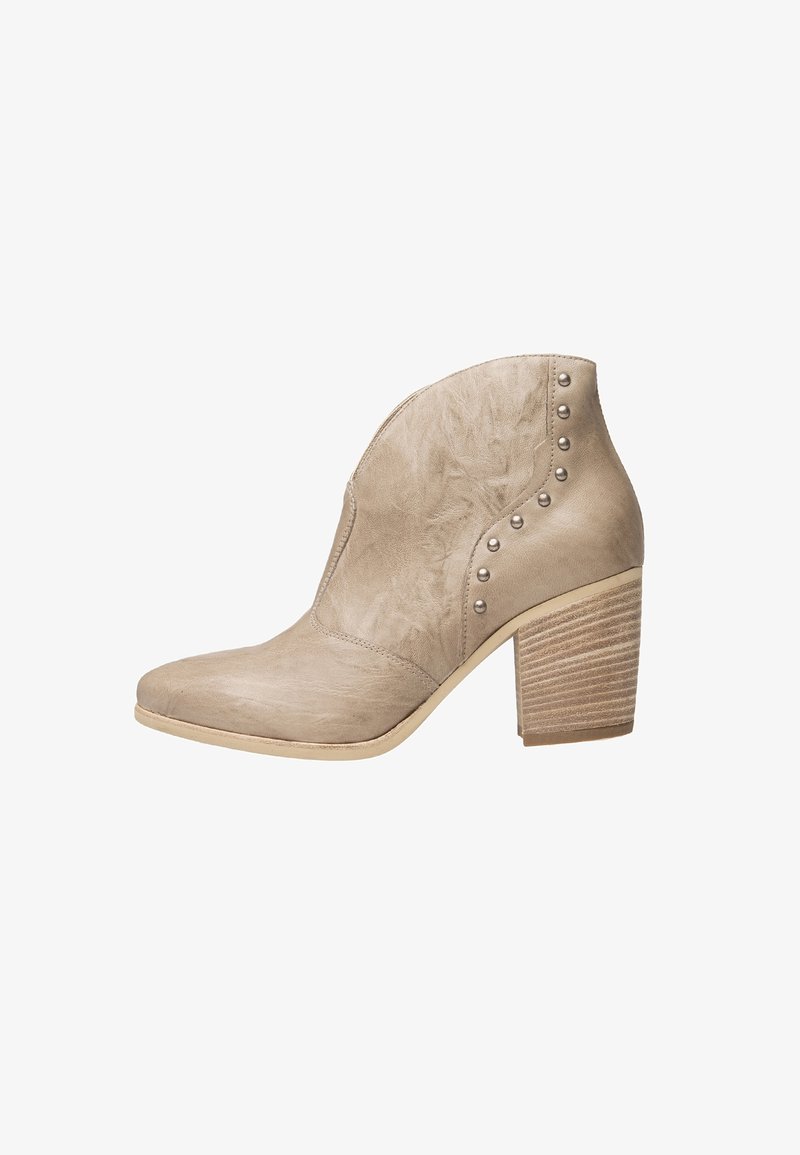 Bottine en cuir beige avec un bout pointu, une tige texturée, des clous latéraux, et un talon en bois empilé.