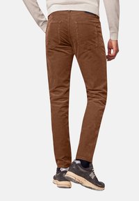 Bruine corduroy broek met een slim fit, voorzien van achterzakken en een subtiele verticale ribbelstructuur. Geldig met een lichtgekleurde trui en sneakers.