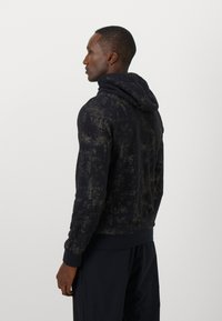 Sudadera con capucha en azul marino oscuro con un patrón abstracto texturizado en verde. Presenta puños y dobladillo acanalados, diseñada para proporcionar comodidad y calidez.