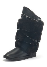 Schwarze Stiefel bis zur Mitte der Wade mit einem glatten Lederäußeren, weichem Futter aus Fell mit geschichteten Abschnitten und silbernen Kettenakzenten auf der Vorderseite.