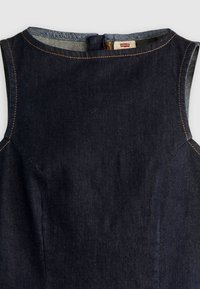 Σκούρο μπλε μίντι φόρεμα από τζιν χωρίς μανίκια με στρογγυλή λαιμόκοψη και εμφανείς πορτοκαλί ραφές, με μικρή ετικέτα Levi's μέσα στον γιακά.