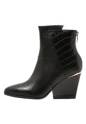 Black ankle boot featuring a smooth leather front, crocodile pattern side, pointed toe, and a wedge heel with gold accent. Side zipper closure.