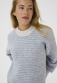 Light blue and white striped sweater with a ribbed crew neck, featuring a textured, plush fabric and a relaxed fit.