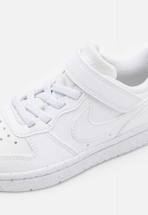 Białe sneakersy z gładką syntetyczną cholewką, zaokrąglonym czubkiem, sznurowanym zapięciem oraz rzepem. Mają teksturowaną podeszwę z nakrapianymi akcentami.