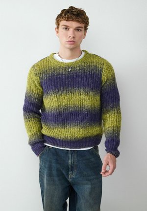Gestrickter Pullover in leuchtendem Grün und lila horizontalen Streifen, mit gerippter Textur und Rundhalsausschnitt. Trägt man über einem weißen Hemd und kombiniert mit Jeans.