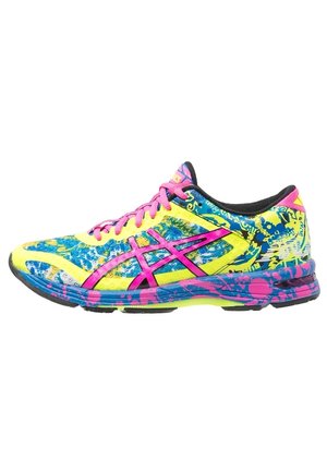 Chaussure de course multicolore avec un design éclaboussé jaune, bleu, rose et noir et des lacets roses, présentée sur fond blanc.