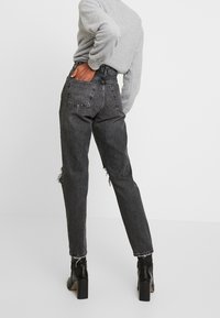 Černé džíny s vysokým pasem a volným střihem, s efektivními odřenými detaily a třepeným lemem. Vyrobeno z denimu s vybledlým vzhledem.