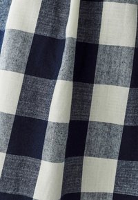 Tejido a cuadros en azul y blanco con textura de lino; presenta grandes cuadros alternos de diferentes tonalidades de azul y marfil.