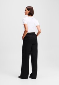 Witte katoenen t-shirt met korte mouwen en zwarte elastische taillebandbroek. De broek heeft zakken en een losse pasvorm, ontworpen voor comfort.