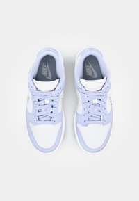 Ett par vita och ljuslila Nike-sneakers med snören, sedd ovanifrån på en enkel vit bakgrund.