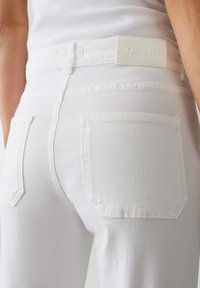 Jeans in denim bianco con una texture liscia, dotati di due tasche posteriori e di un patch del logo OPUS bianco sulla vita.