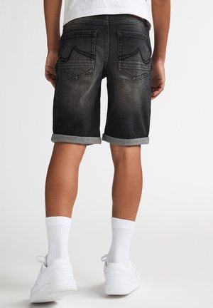 Zwarte denim shorts met omgeslagen zomen, voorzien van twee achterzakken en subtiele vervaging. Draag ze met witte sokken en witte sneakers.