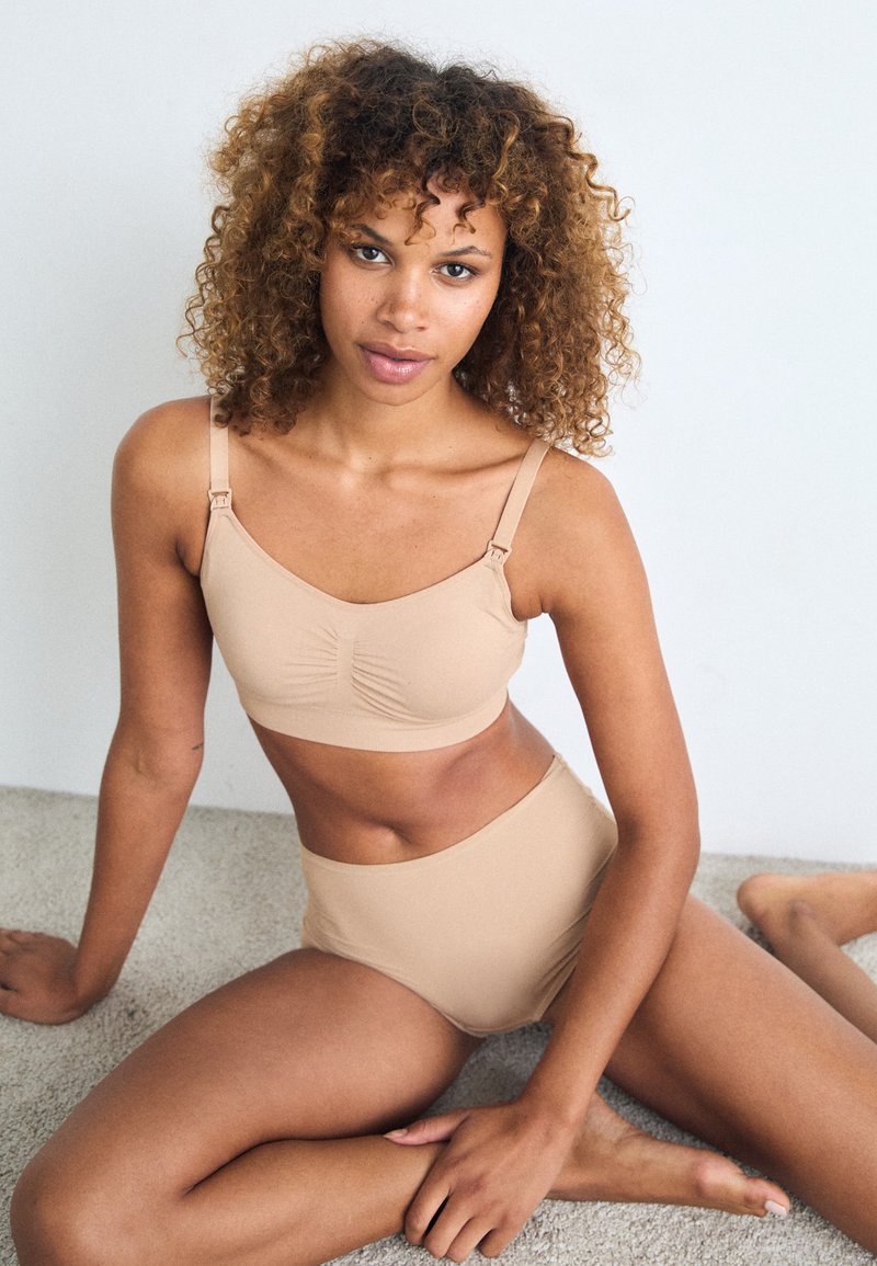 Beige lingerie set consisting of a soft, seamless bra with a gathered center and adjustable straps, paired with high-waisted briefs.