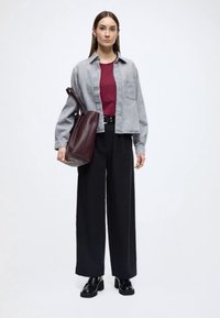 Szürke farmering, bordó felső, széles fekete nadrág és fekete platform cipő. Egy nagy bordó válltáskát visel. Egyszerű, modern kialakítás.